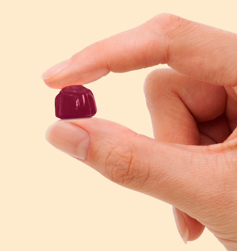 Showing size of gummy hand, holding side view of orange gummy